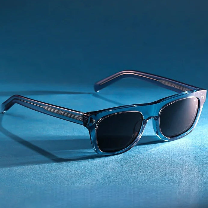 Charlie Polarized Square Sunglasses in Sky displayed on a blue studio surface